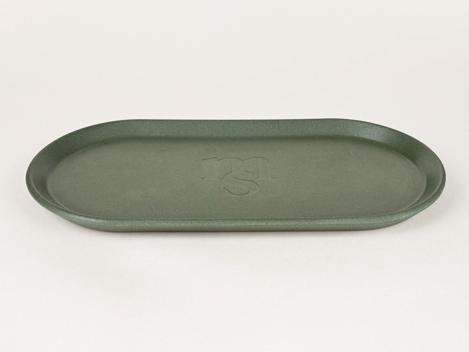 Photograph of a green jesmonite tray against an off-white background