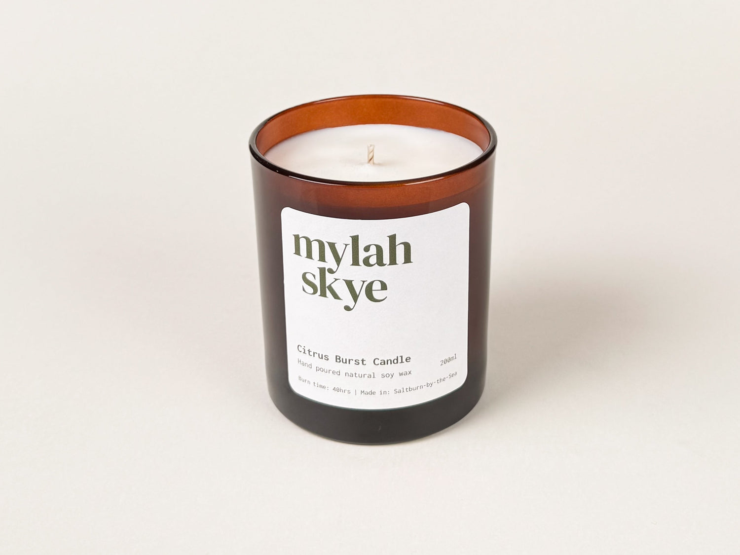 Photograph of an amber glass candle jar against an off white background