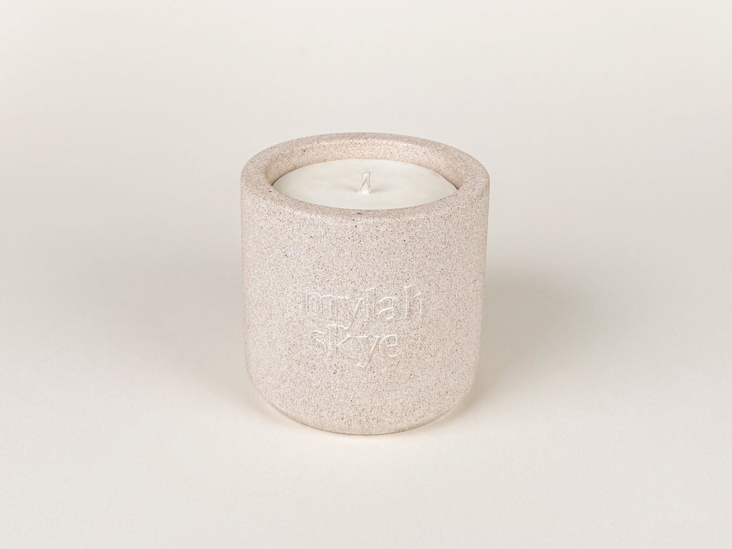 Photograph of an oatmeal coloured jesmonite candle holder against an off white background